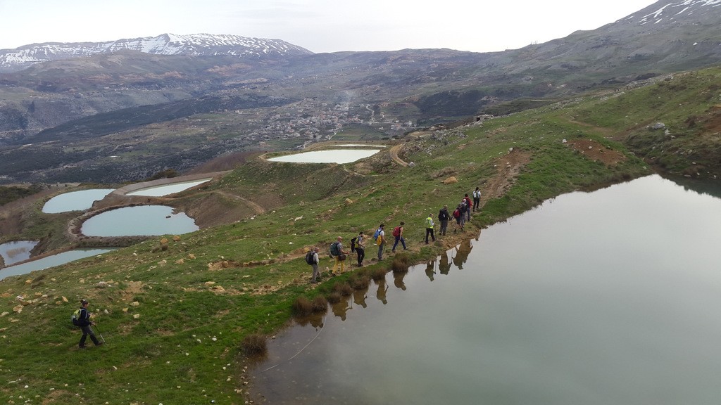 Hikers walking through a mountain lake landscape