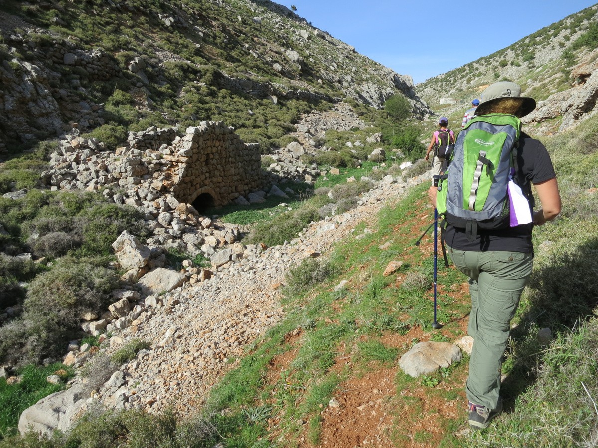 Hikers on a mountain path, walking past small ancient remains